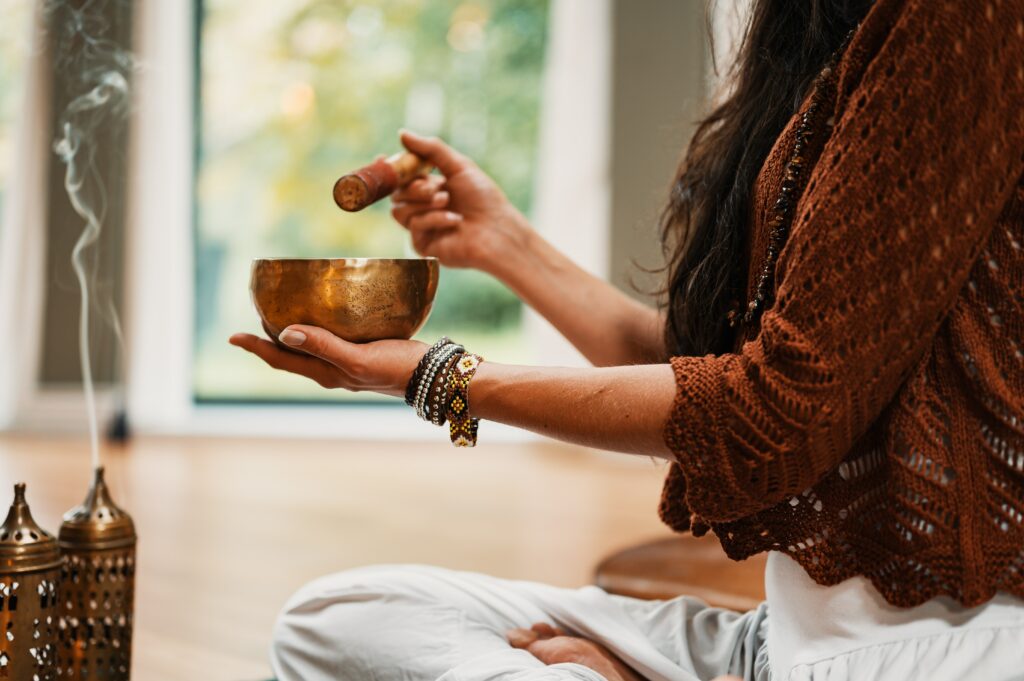 Woman uses a singing bowl as an instrument in sound healing therapy.